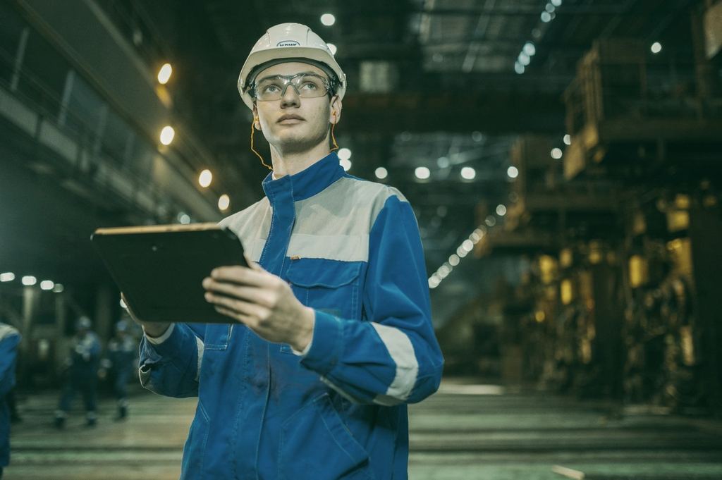 Técnico con casco y tableta en una nave industrial